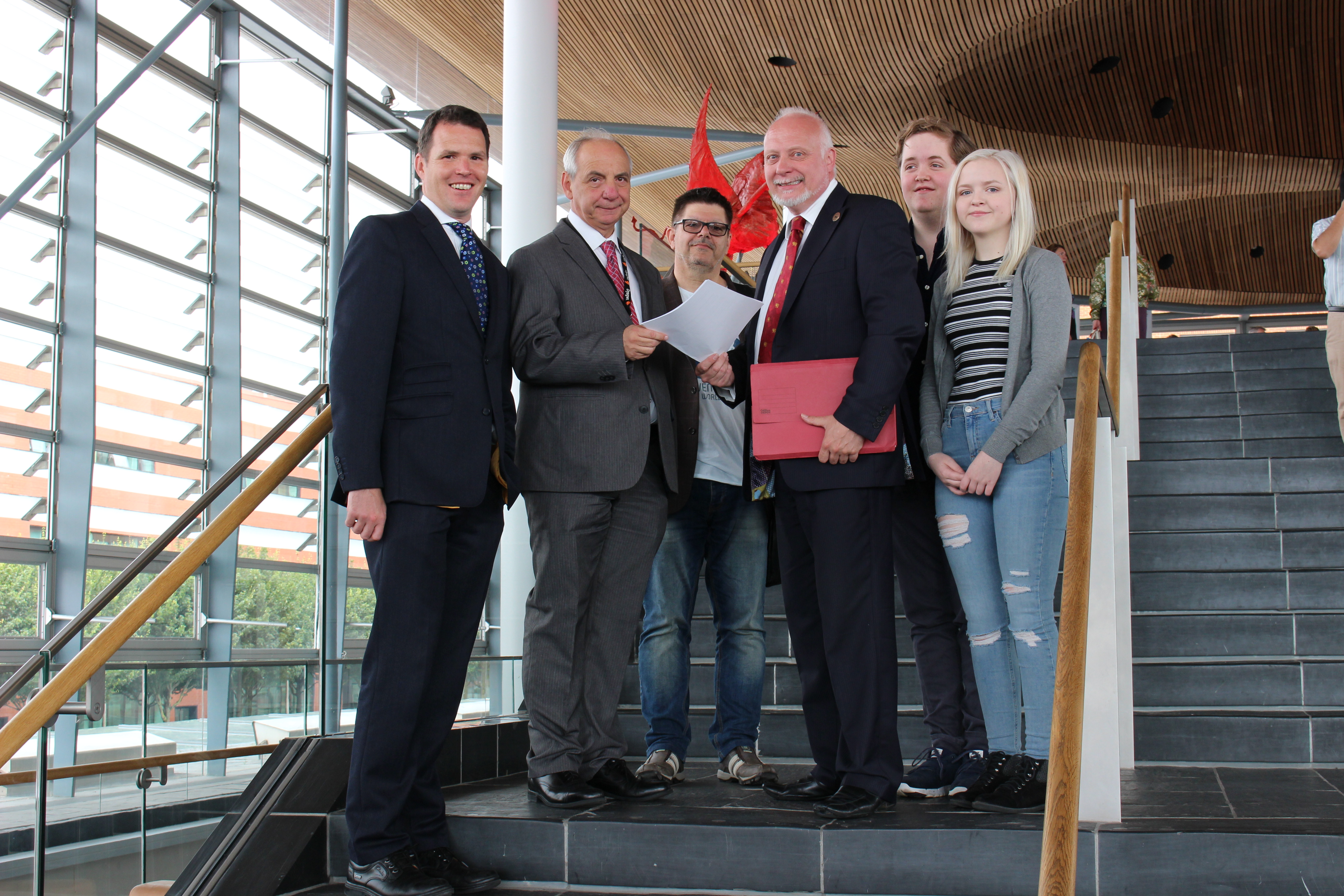 Petitioners present their petition to Mike Hedges AM and Rhun ap Iorwerth AM on the Senedd steps