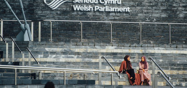Two people sat on the slate steps of the Senedd building.