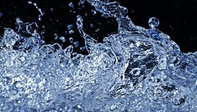 Close-up of splashing water with droplets frozen in motion against a dark background.