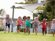 A group of small children running on grass. 