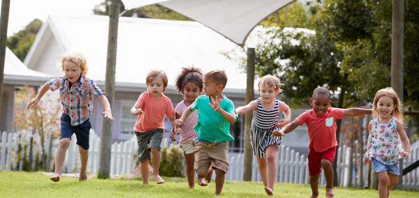 A group of small children running on grass. 