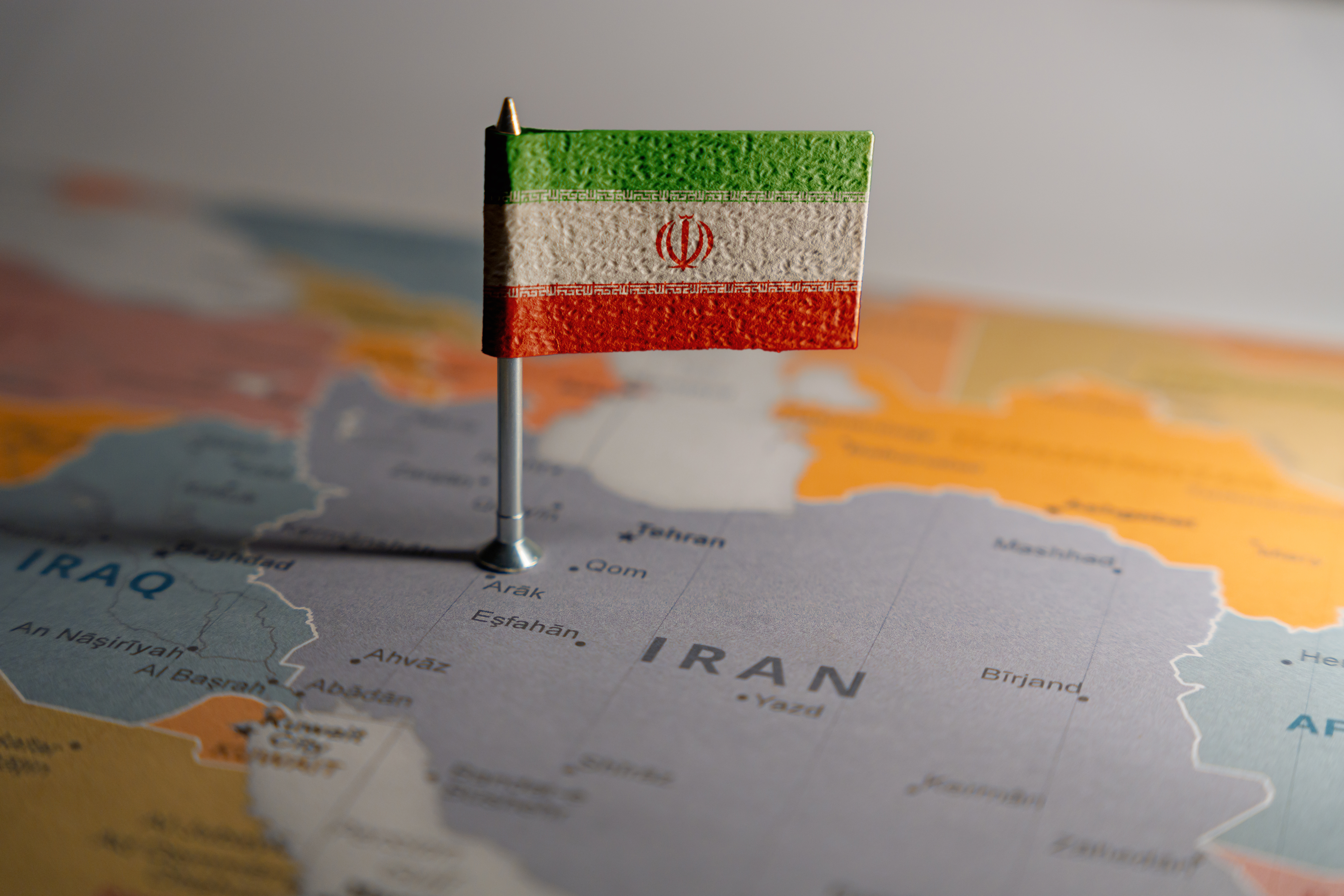 A small Iranian flag pinned on a map, marking the location of Iran