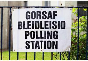 A sign tied to a fence. The text on the sign reads ‘Polling Station’. 