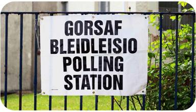 A sign tied to a fence. The text on the sign reads ‘Polling Station’.