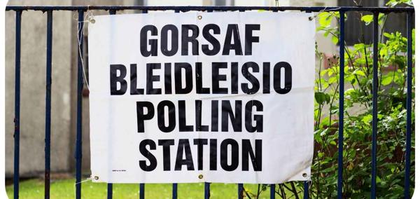 A sign tied to a fence. The text on the sign reads ‘Polling Station’.