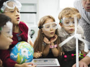 Children in a science lesson with one holding a small globe.