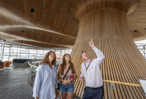 Richard pointing at the Senedd funnel with two visitors.
