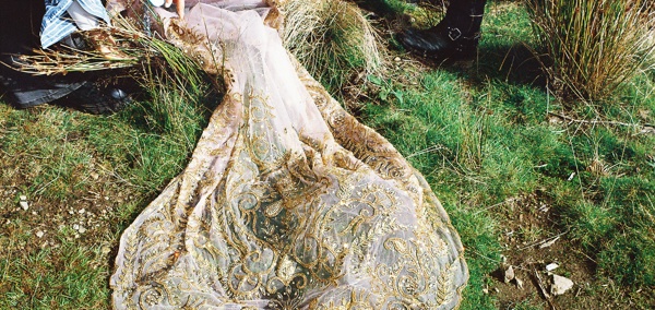 Close-up of a gold-embroidered dress train spread over green grass