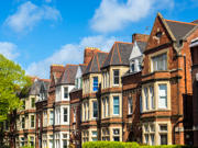 Row of traditional brick houses on a sunny day, with blue sky and a tree to the left