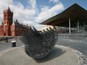 An image of the Senedd and Pierhead buildings, with a sculpture in the foreground. 