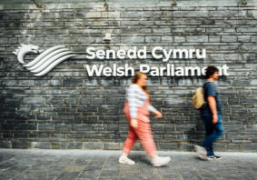 People walking past the Senedd signage