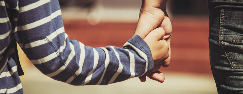 Carer and child holding hands
