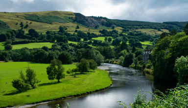 Image of river bend in a Welsh farming landscape, with hilltop quarry in the distance.