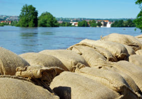 A photograph of sandbags in front of a flooded river.