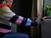 Woman warming her hands by the radiator