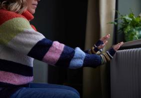 Woman warming her hands by the radiator
