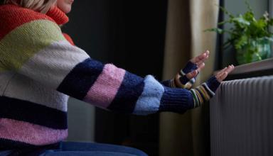 Woman warming her hands by the radiator