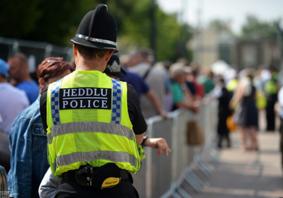 A uniformed police officer wearing a high-visibility yellow vest, standing outdoors, symbolising frontline policing and public visibility.